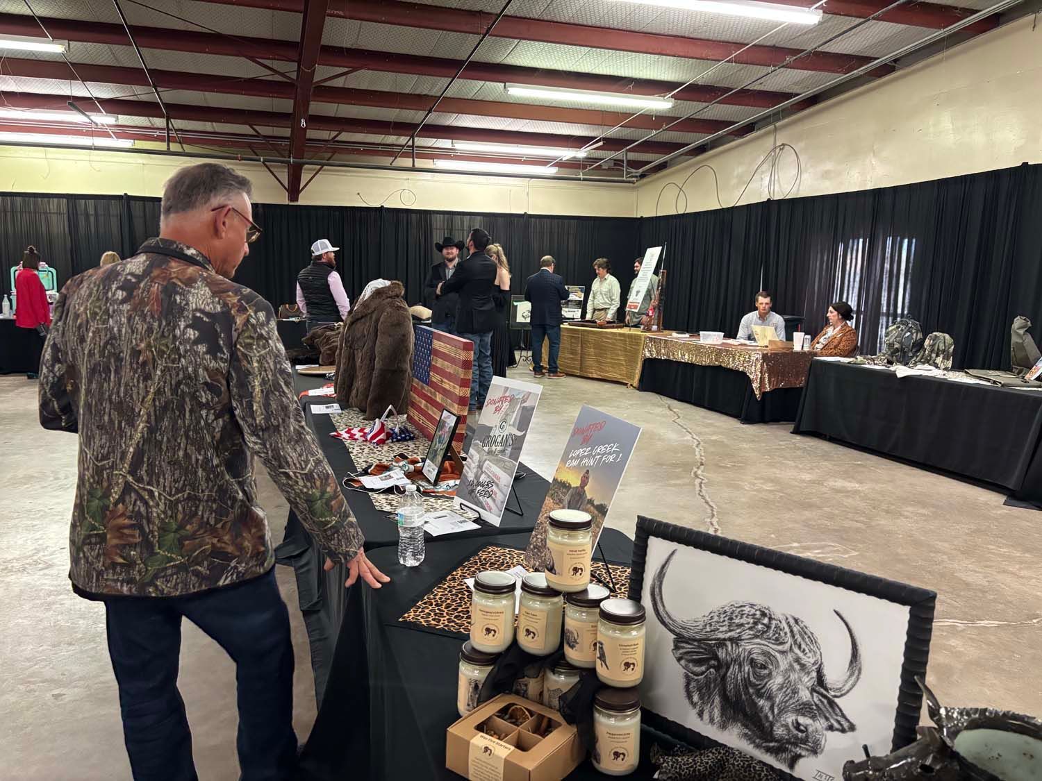 Indoor craft fair with vendor tables, artwork, and a man browsing displays