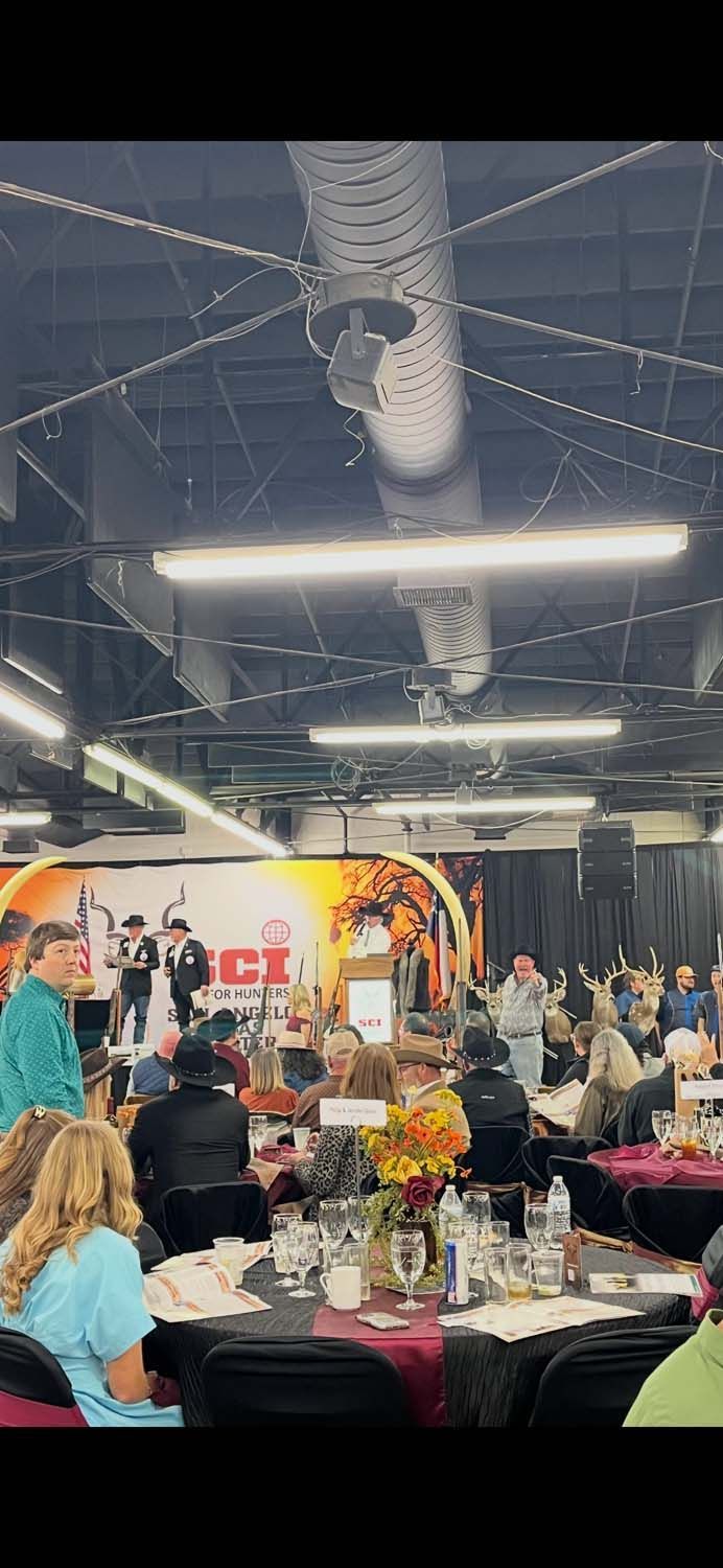 Indoor banquet with round tables, seated guests, floral centerpieces, and hanging industrial lights above.