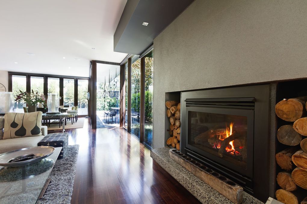 Modern living room with a sleek fireplace, polished wood floors, and floor-to-ceiling windows
