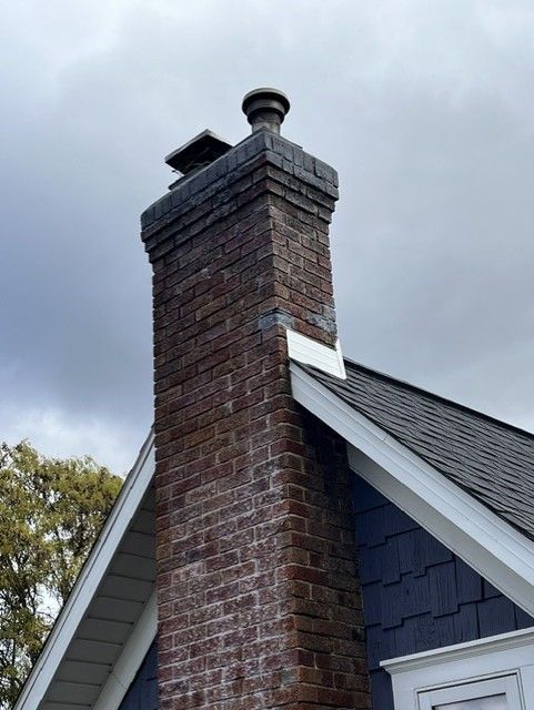 Brick chimney on a house roof against a cloudy sky