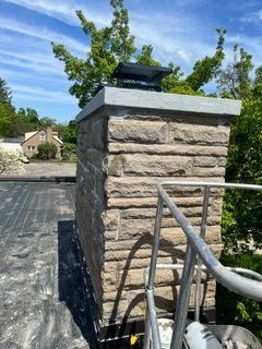 Stone pillar beside metal railing under a blue sky in a residential driveway