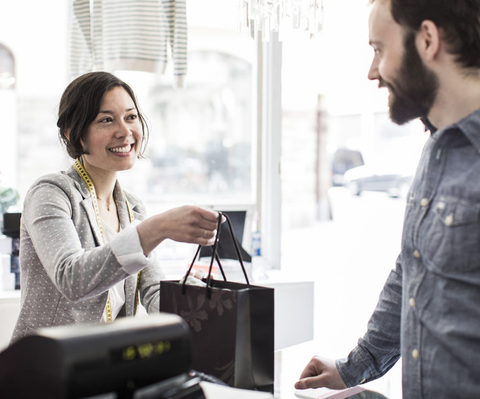Happy worker at checkout counter in store