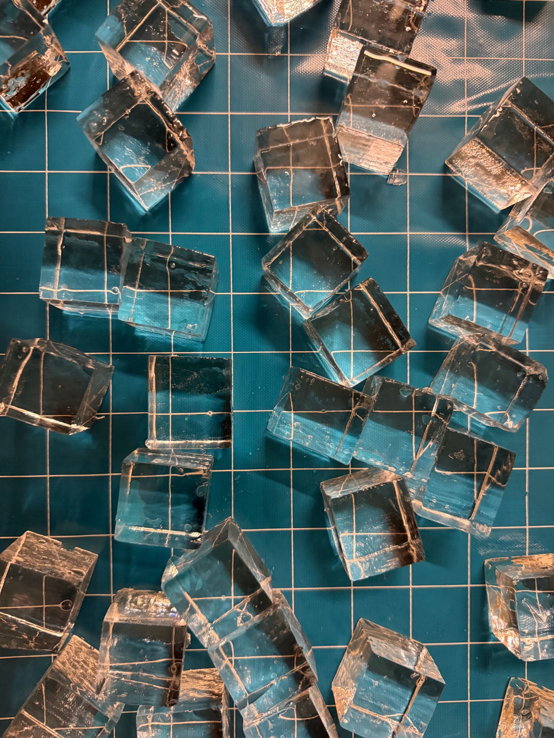Assorted clear glass cubes scattered on a teal tiled surface