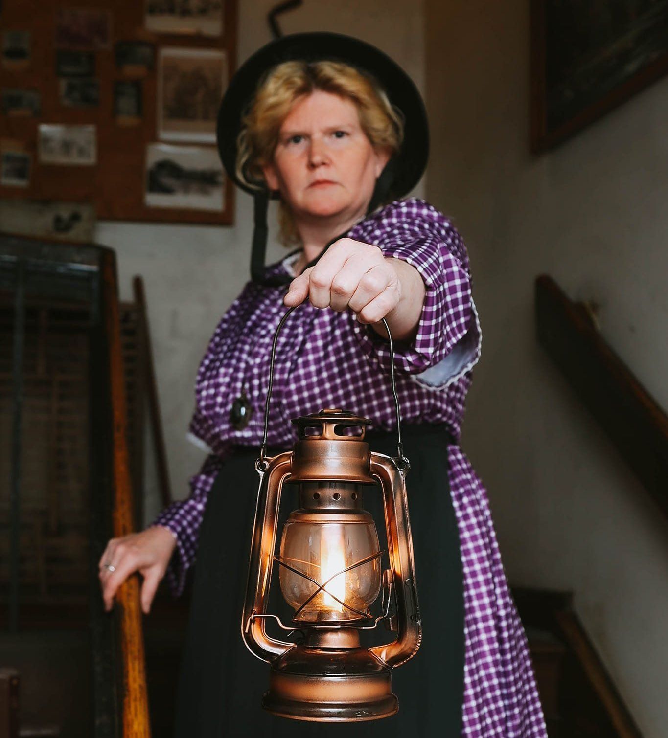 A woman in a plaid shirt is holding a lantern