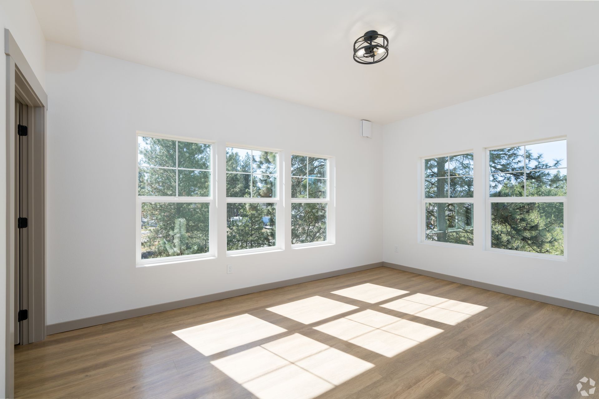 An empty room with hardwood floors and lots of windows.
