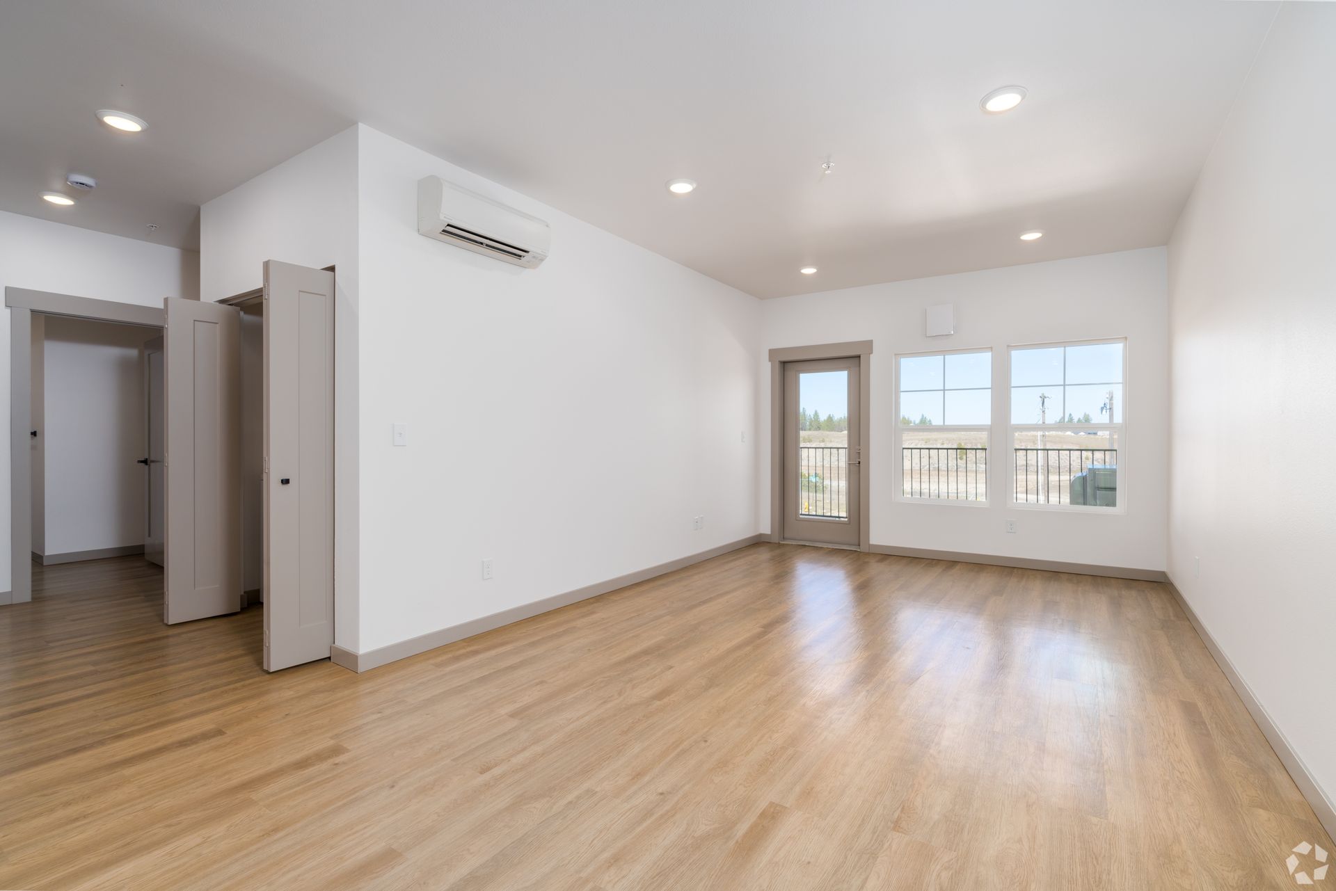An empty living room with hardwood floors and white walls.
