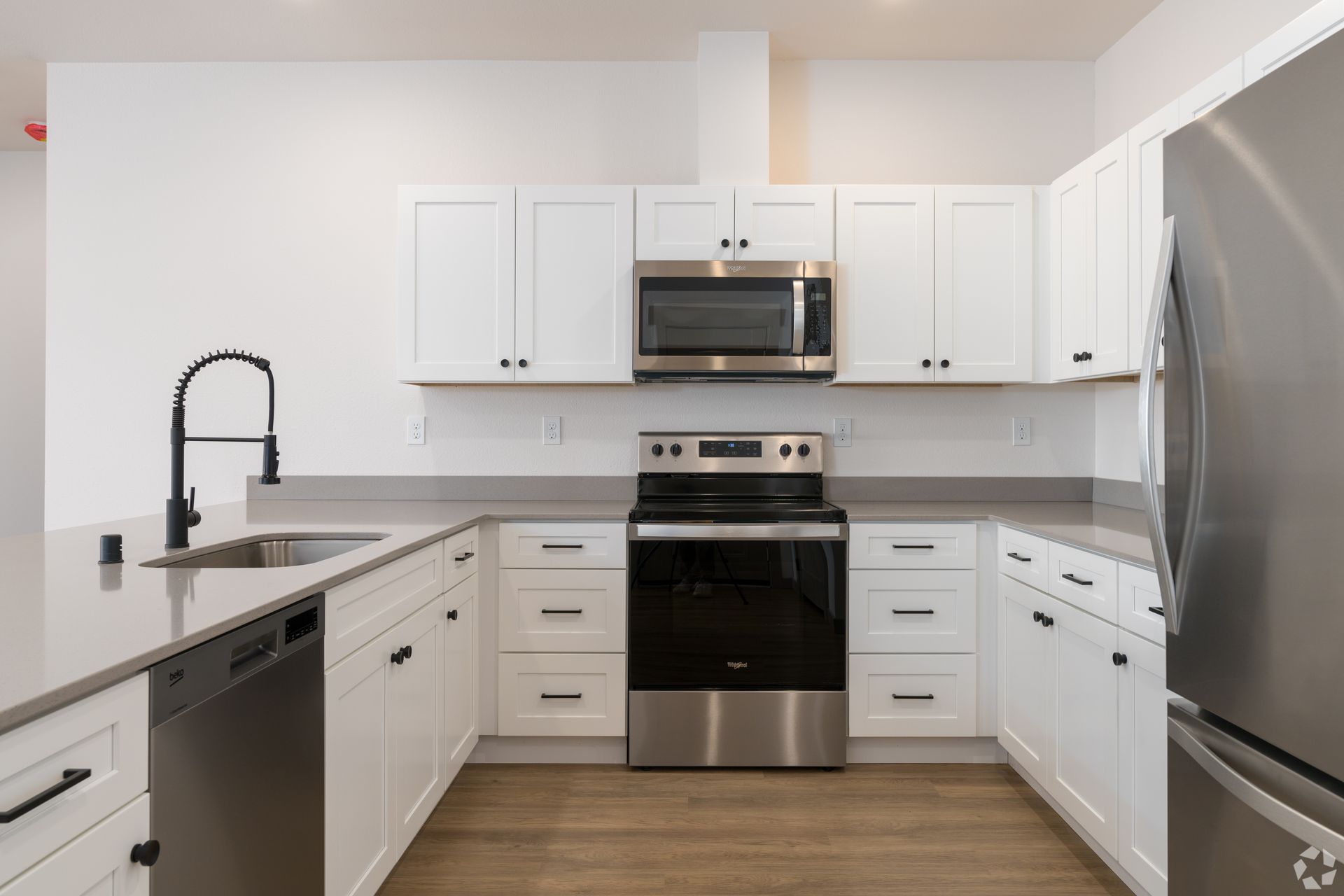 A kitchen with white cabinets , stainless steel appliances , a sink , and a refrigerator.