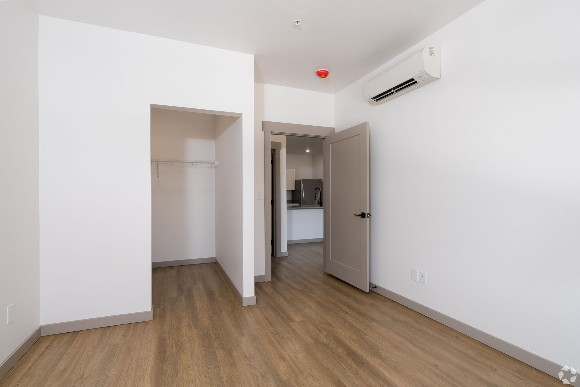 An empty room with hardwood floors and white walls.