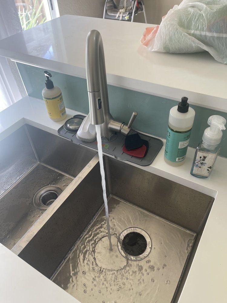 A kitchen sink with water running from the faucet.