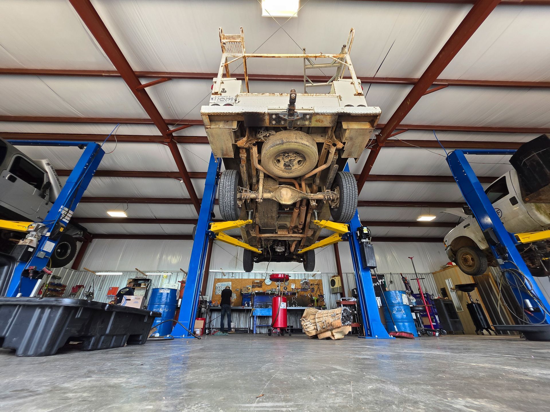 Technician inspecting driveshaft and axle under a vehicle on a lift