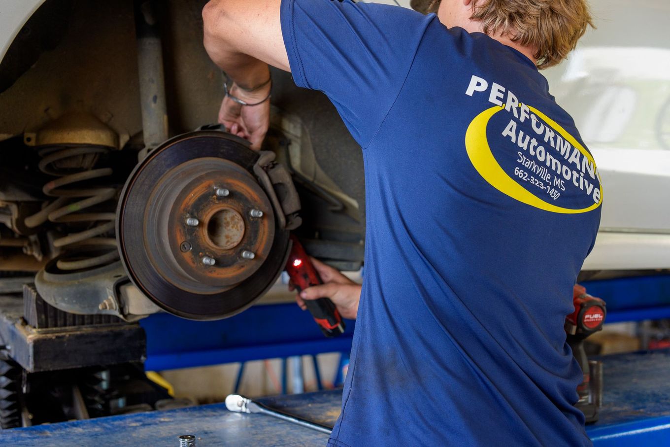 Technician performing a brake inspection with wheel removed