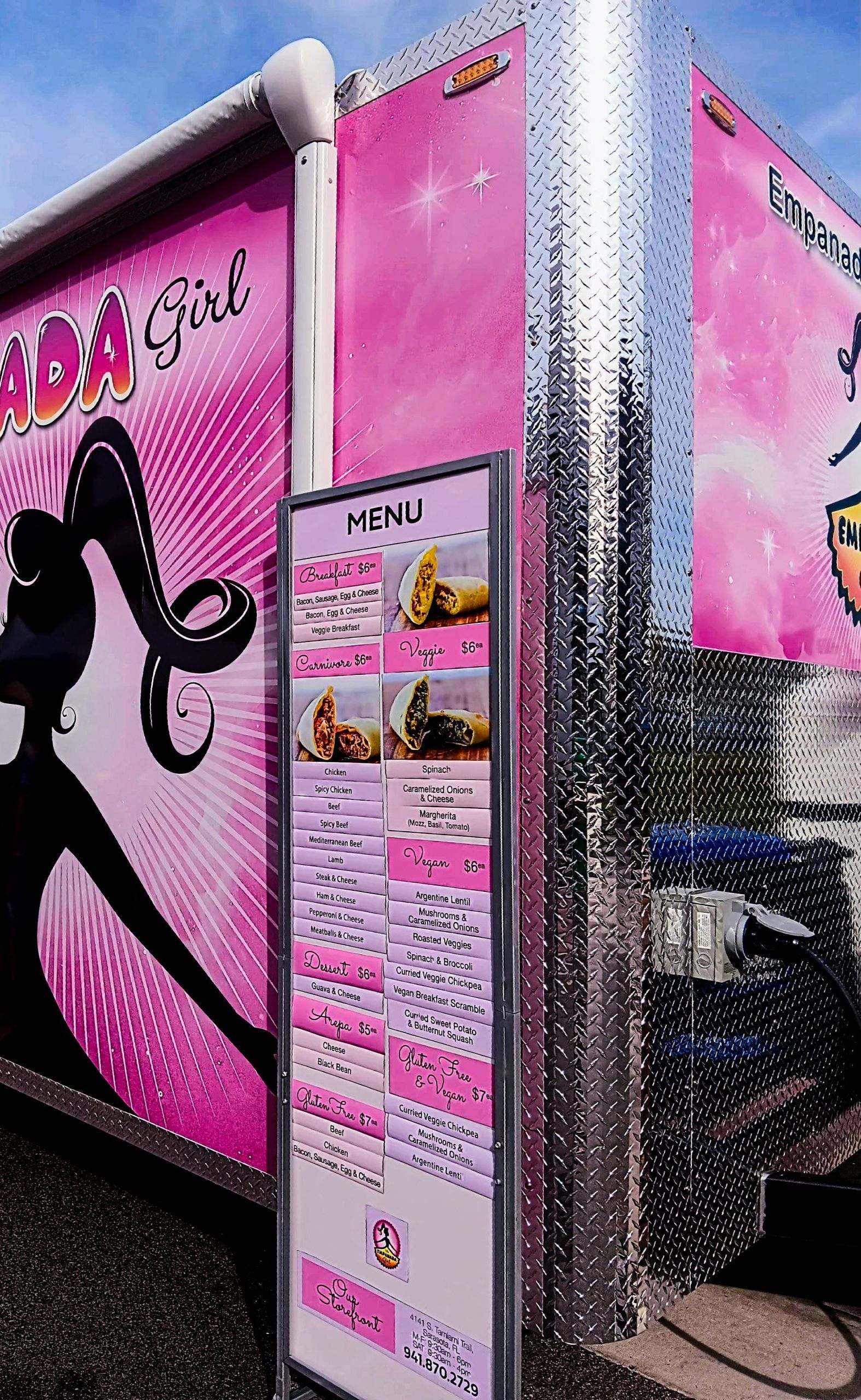 A pink food truck with a menu on the side of it.