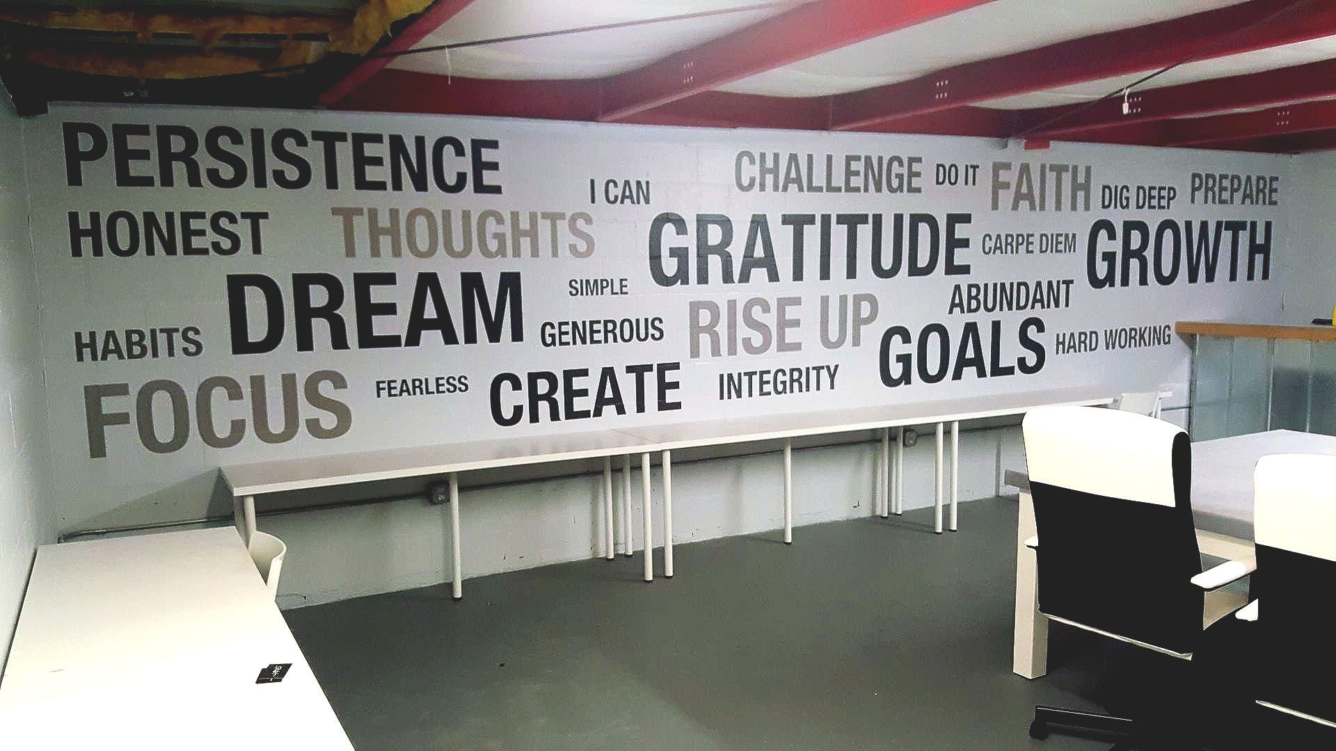 A wall with words such as persistence and honest on it