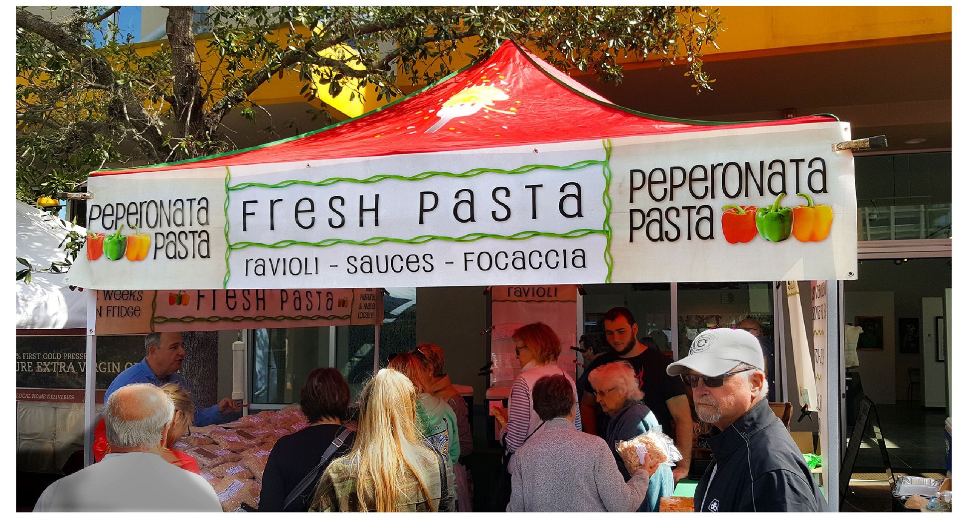 A group of people standing under a tent that says fresh pasta