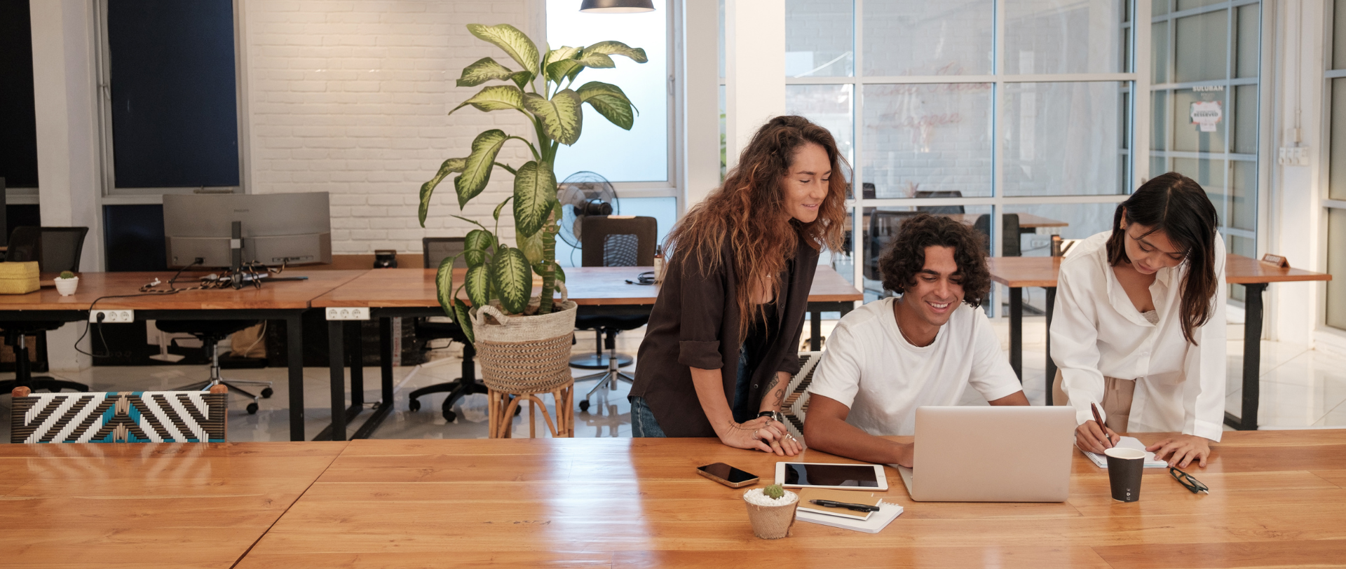 A group of people are sitting at a table looking at a laptop computer.