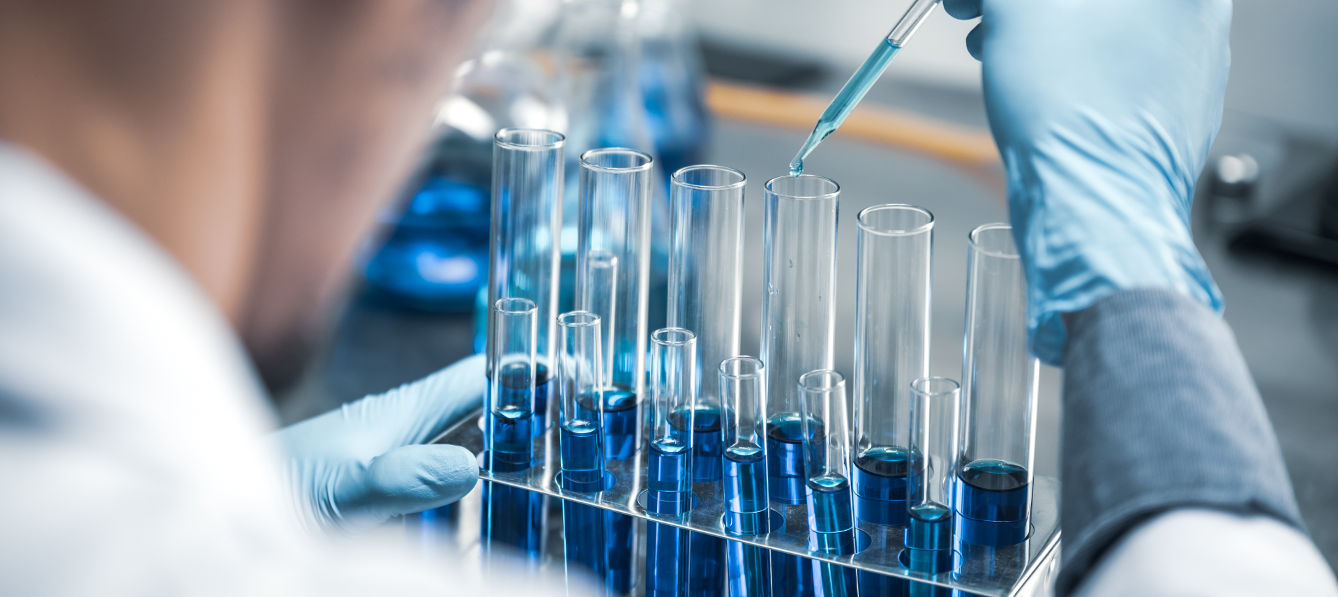 A scientist is pouring liquid into test tubes in a laboratory.