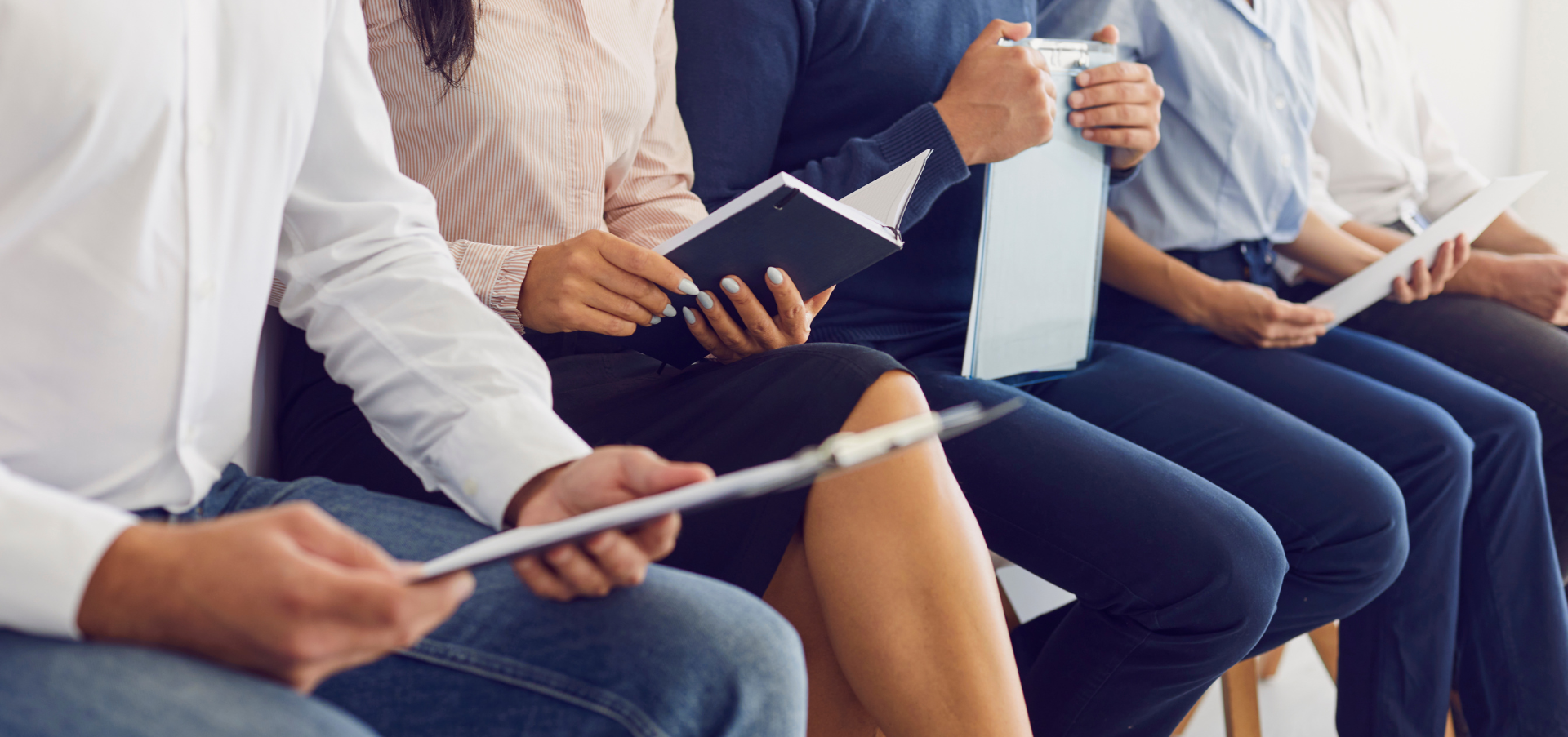 A group of people are sitting in a row waiting for a job interview.
