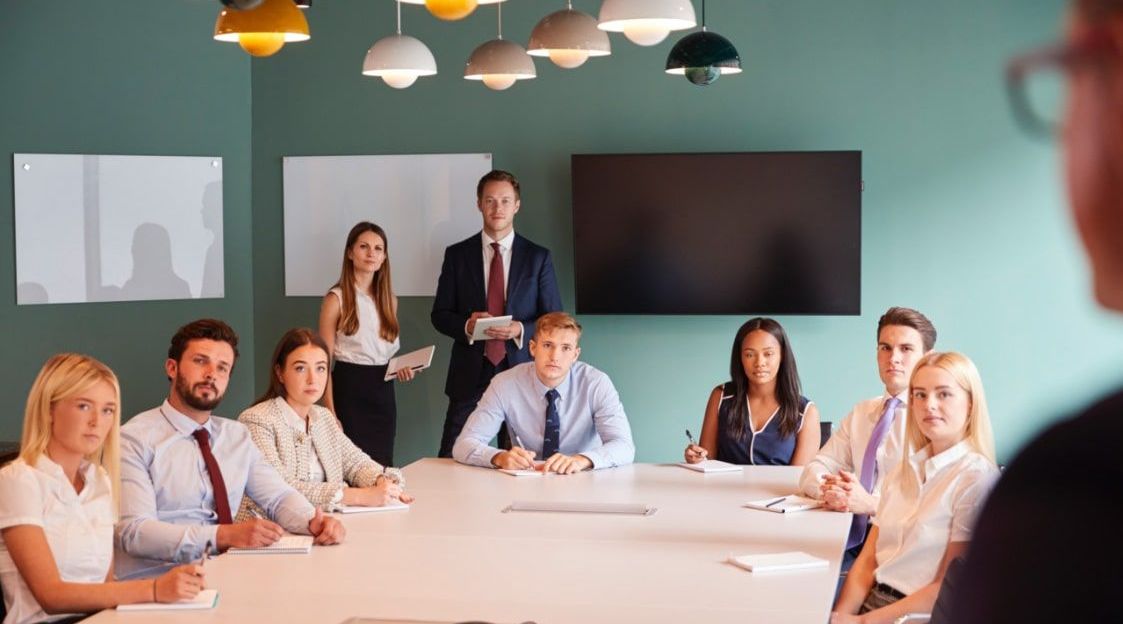 A group of people are sitting around a table in a conference room.