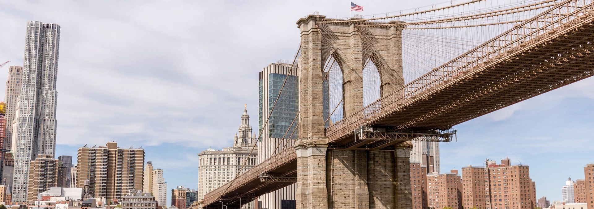 A bridge over a river in new york city with a city skyline in the background.