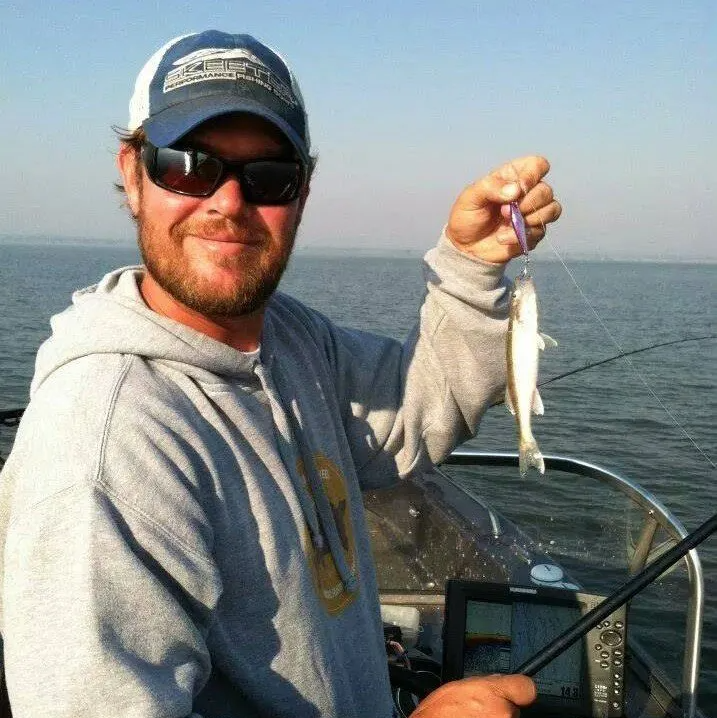 A man on a boat holding a small fish