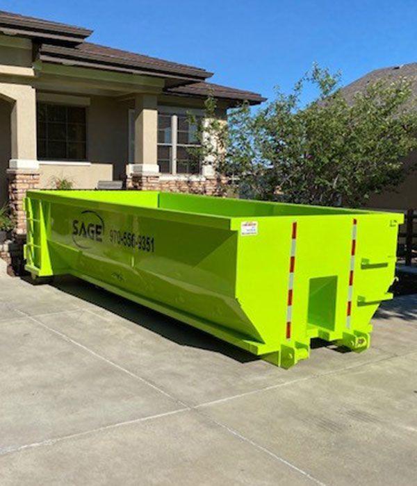 Bright green dumpster in a driveway, in front of a house.