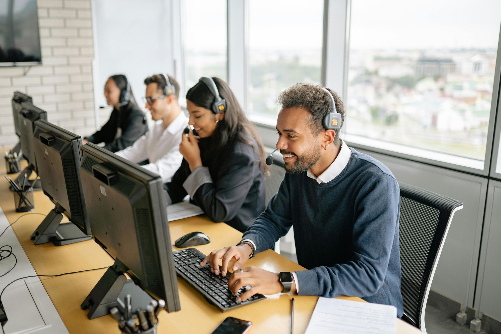 People wearing headsets working at computers in an office setting.