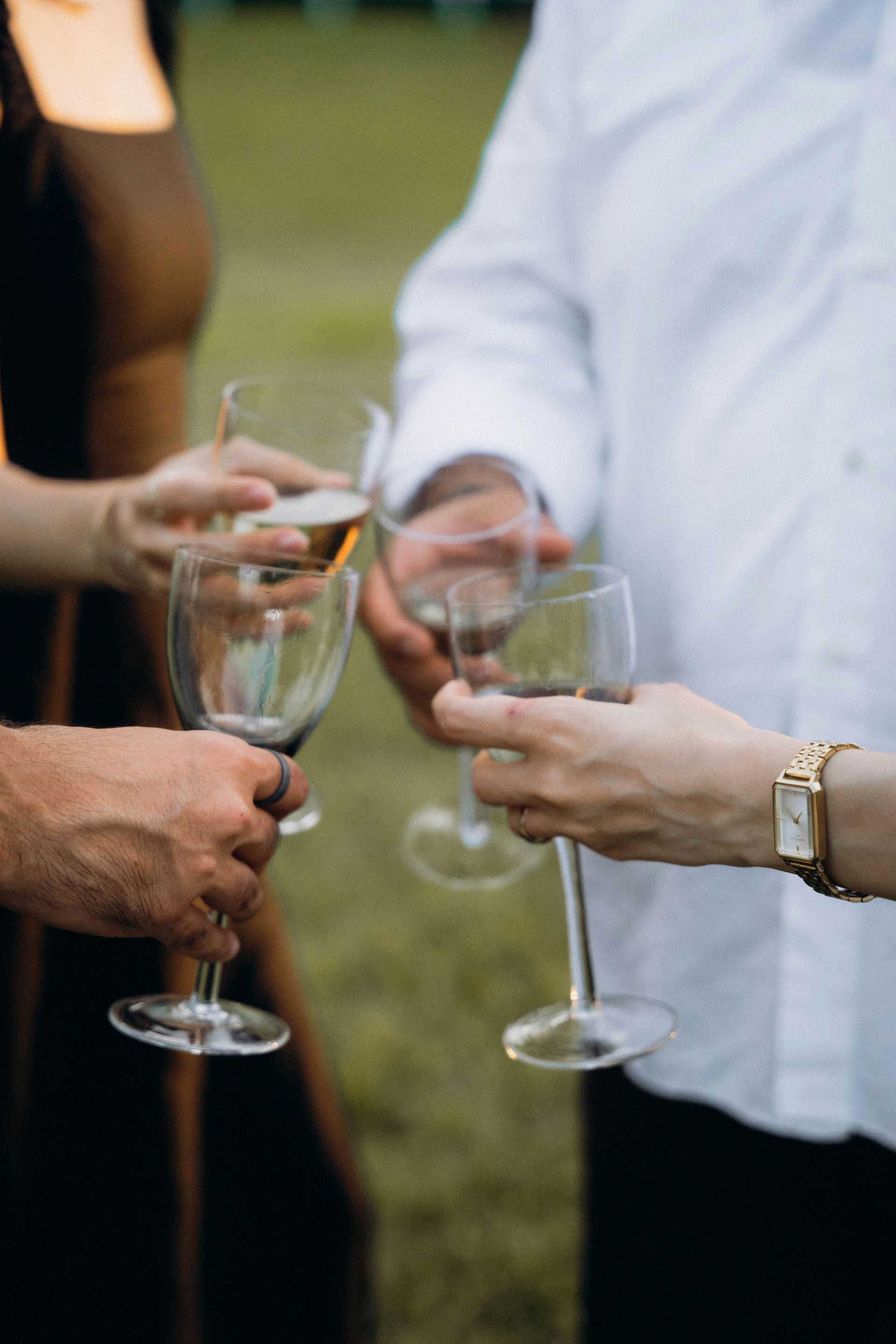 Mensen die champagneglazen vasthouden om te proosten tijdens een bijeenkomst in de buitenlucht.