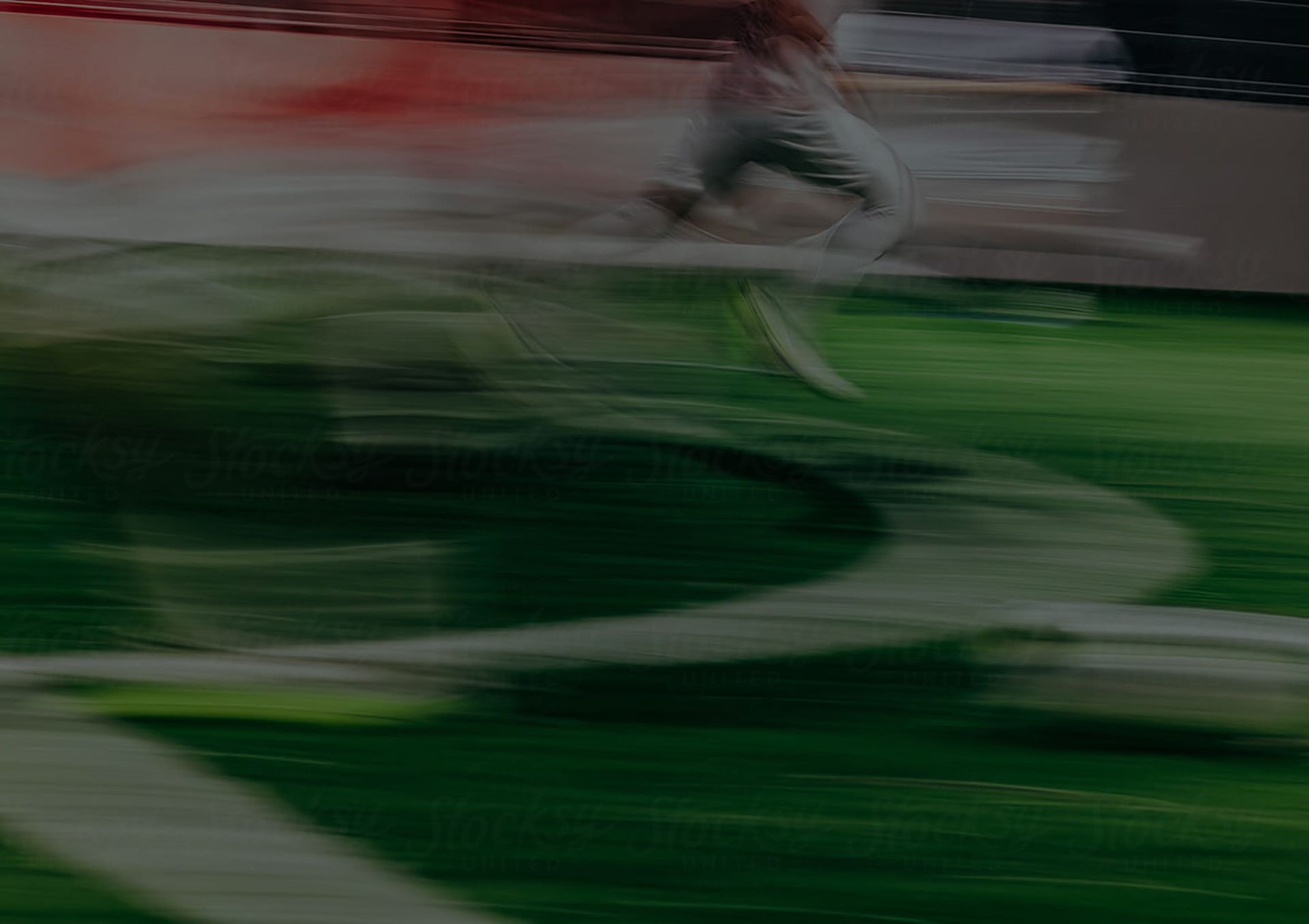Blurred green sports field with a runner in motion near a white track line