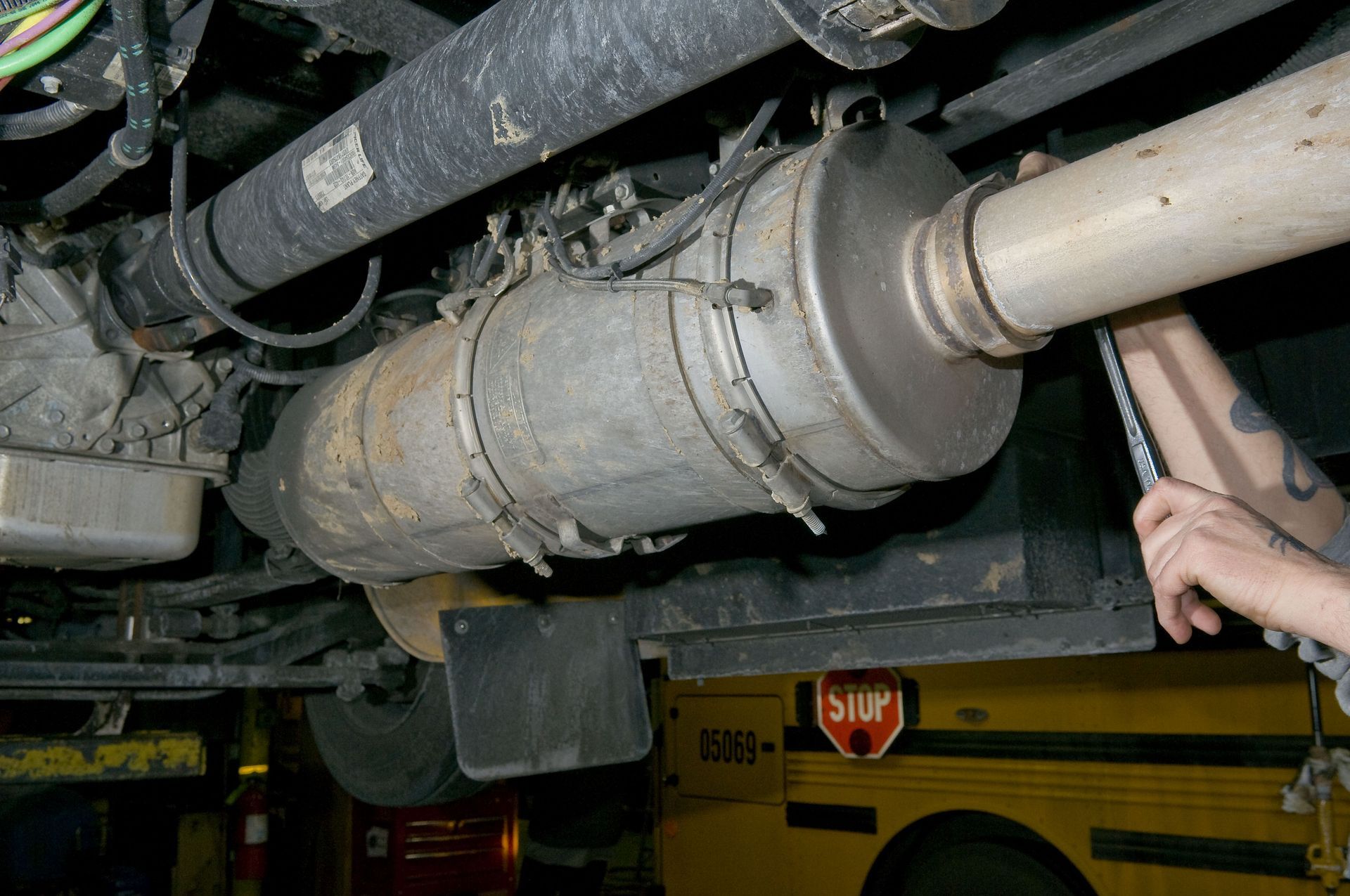 A person is working on the exhaust pipe of a school bus.