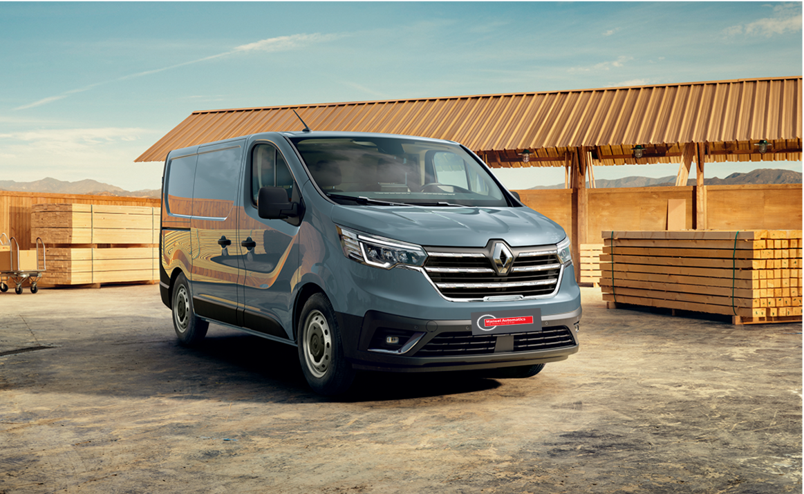 A renault van is parked in front of a wooden building.