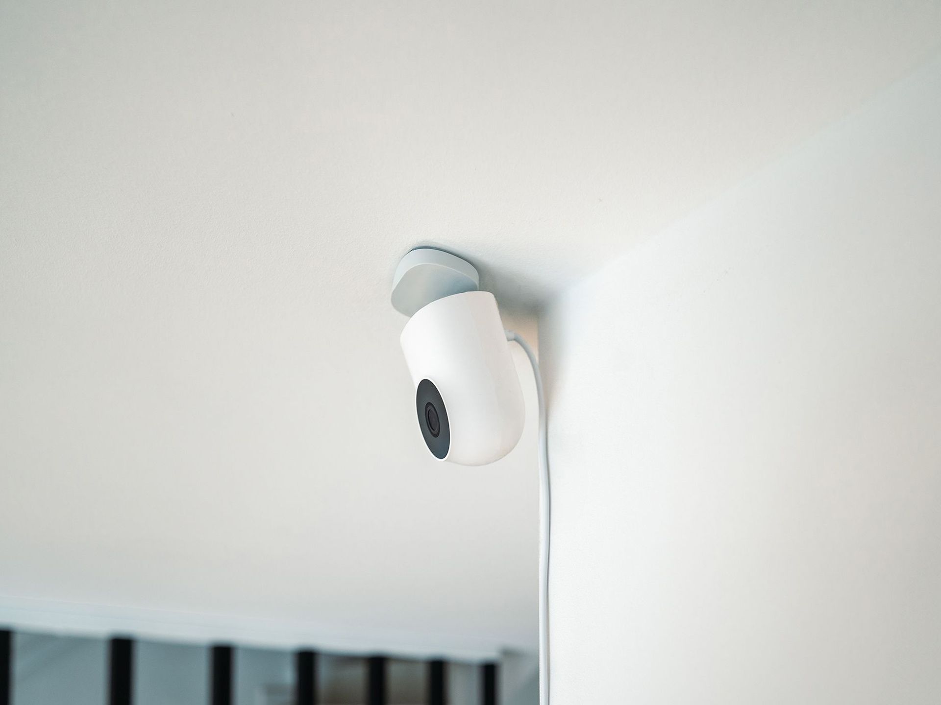 White security camera mounted on a ceiling corner, aimed downward.