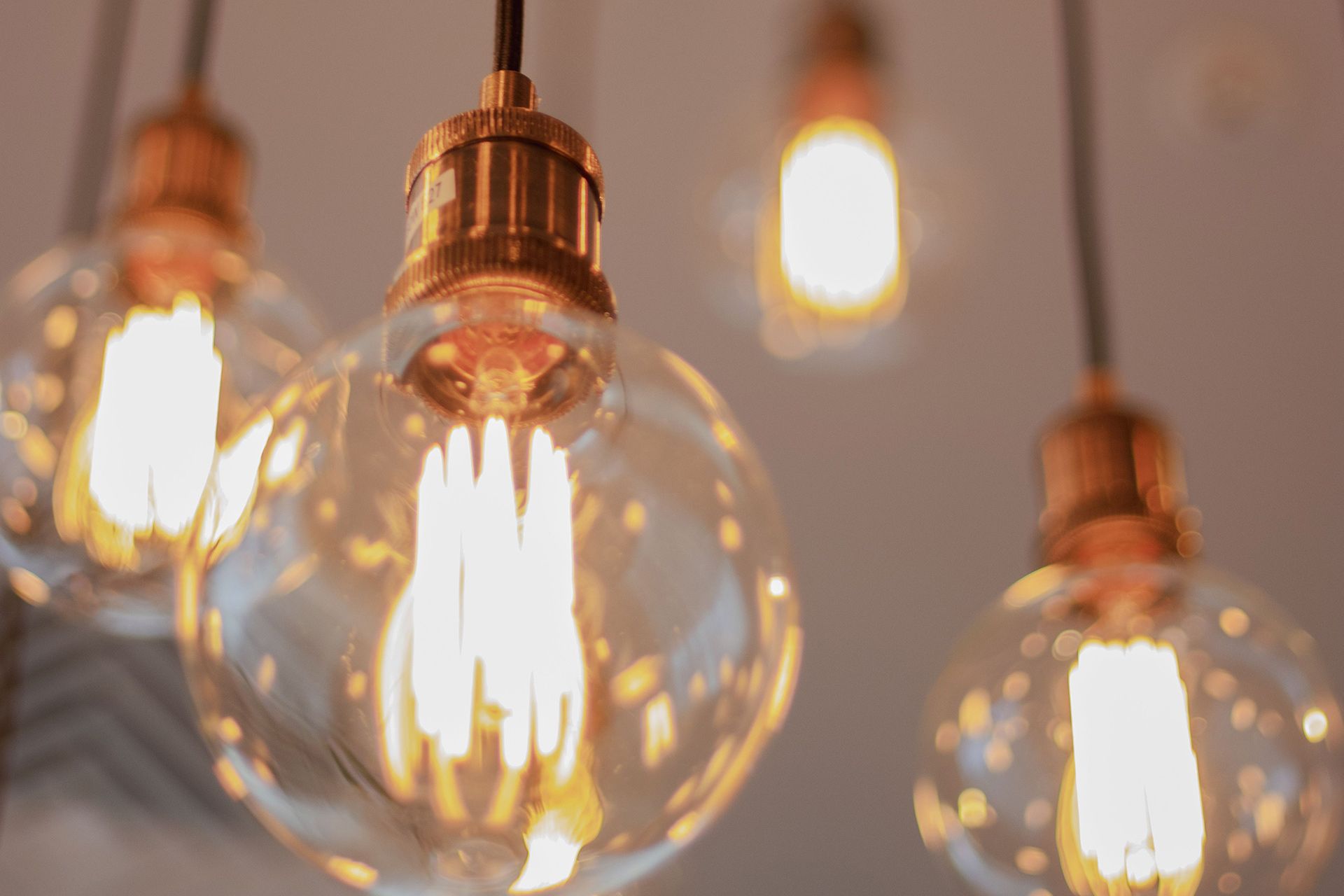 Warm glowing hanging light bulbs with copper fixtures against a blurred background