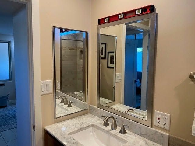 Bathroom vanity with two mirrors and sink, one mirror lit up by daylight from an adjacent room