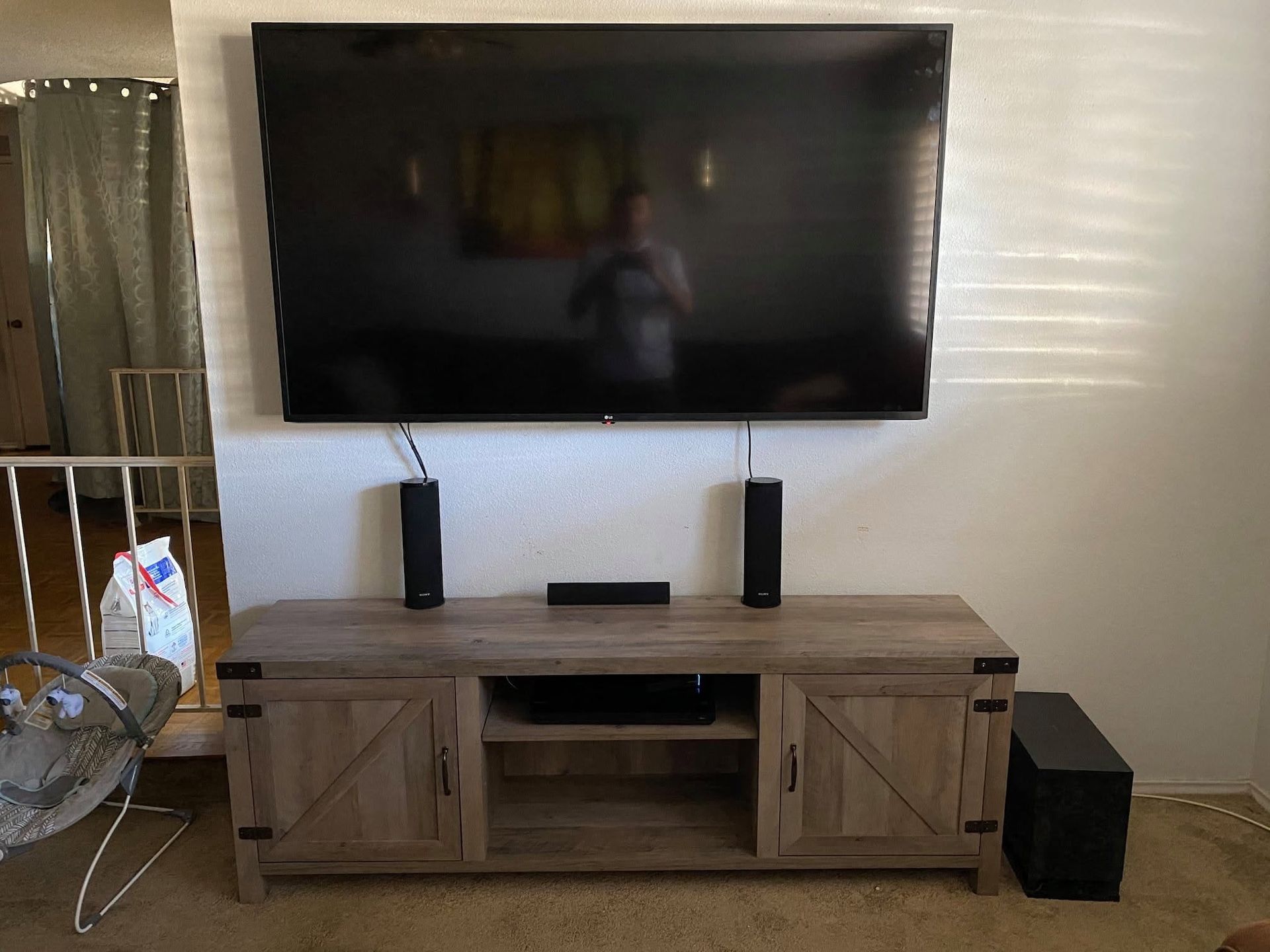 Wall-mounted TV above a wooden console with two speakers in a living room