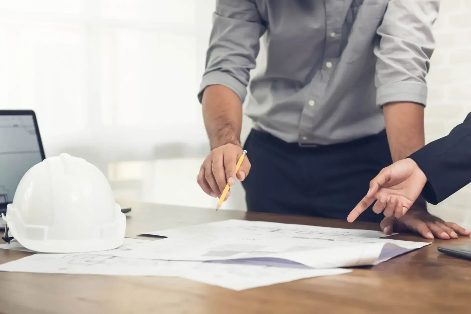 A man and a woman are sitting at a table looking at a blueprint.