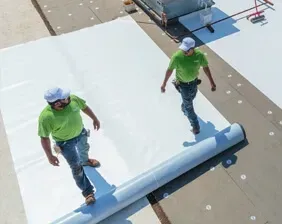 A couple of men are standing on top of a roof.