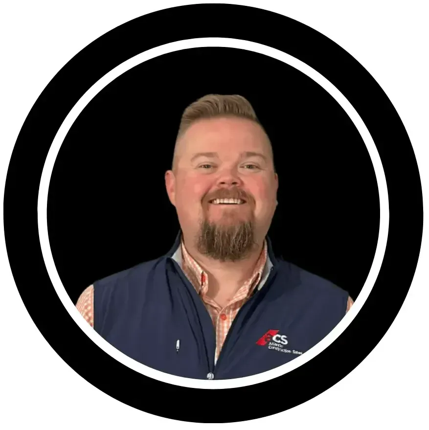 A man with a beard is smiling in a black circle.