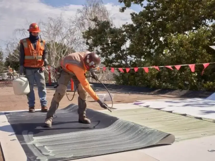 Two construction workers are working on a roof