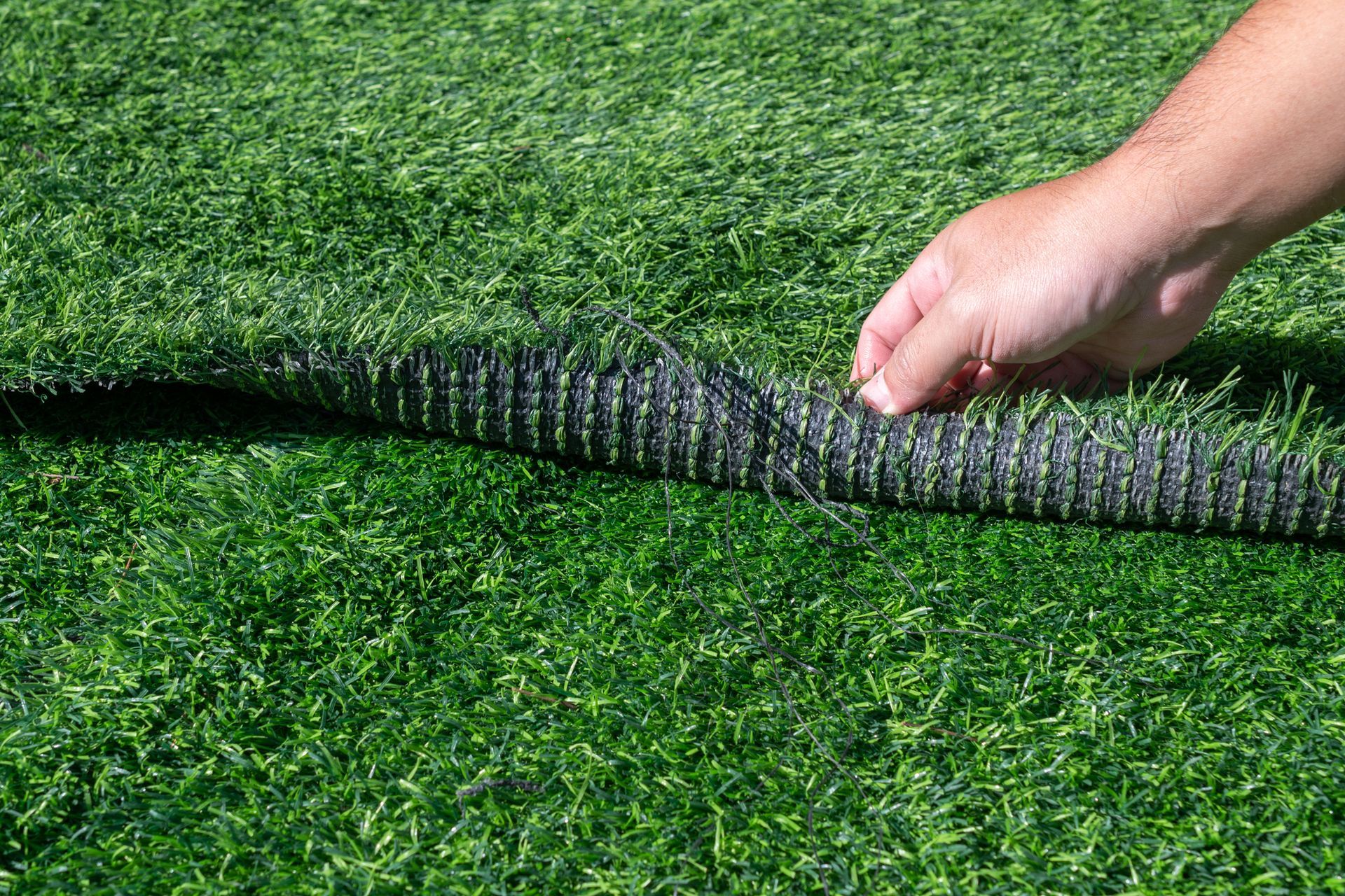 A person is holding a piece of artificial grass in their hand.