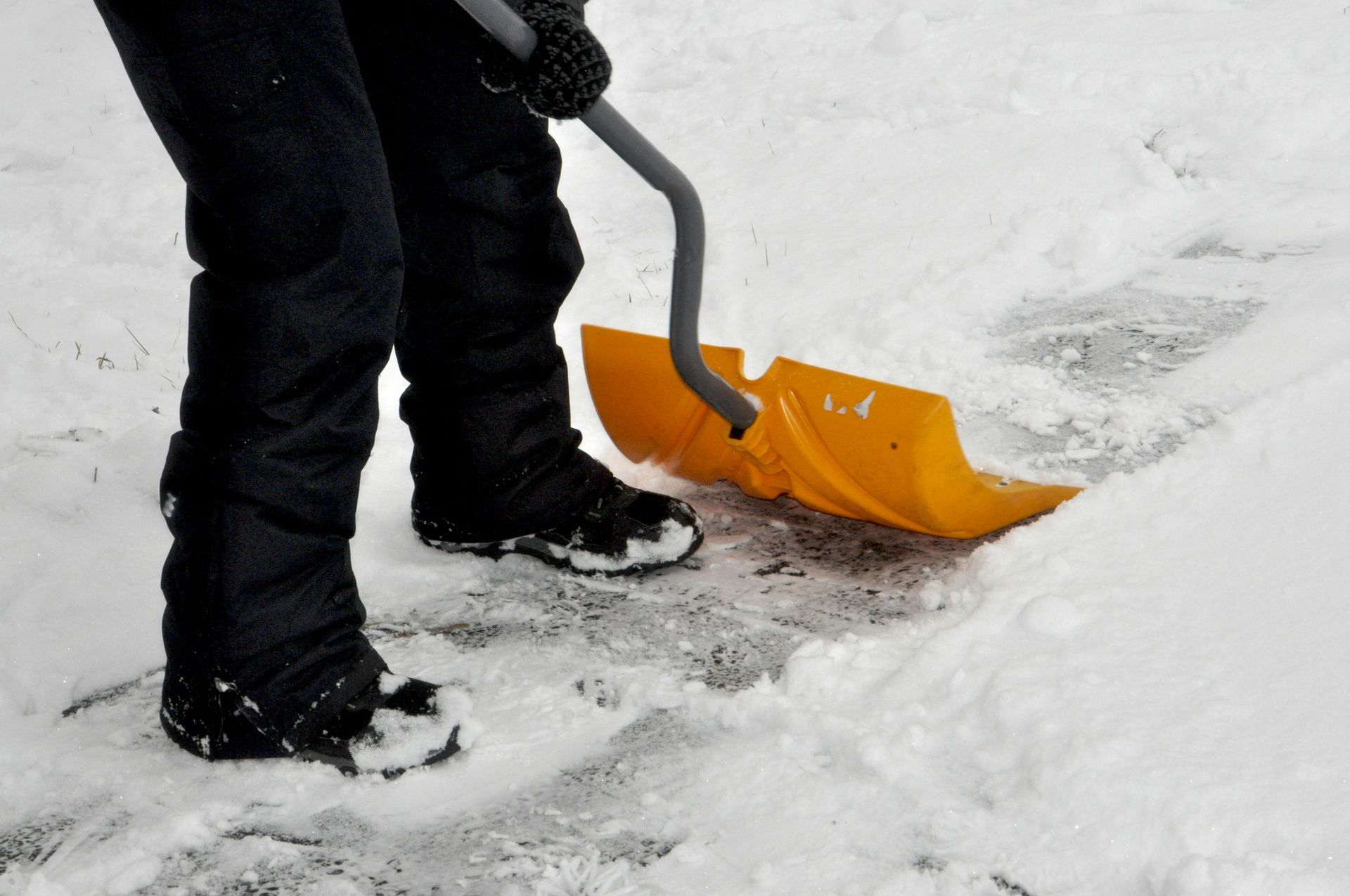 A person is shoveling snow with a yellow shovel