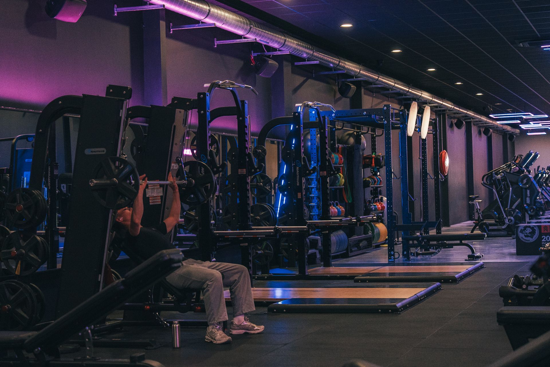 Een sportschool vol met fitnessapparatuur en een blauw plafond.