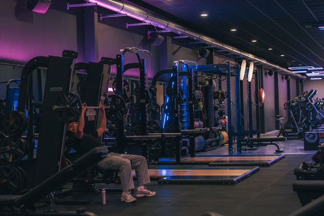 Een sportschool vol met fitnessapparatuur en een blauw plafond.
