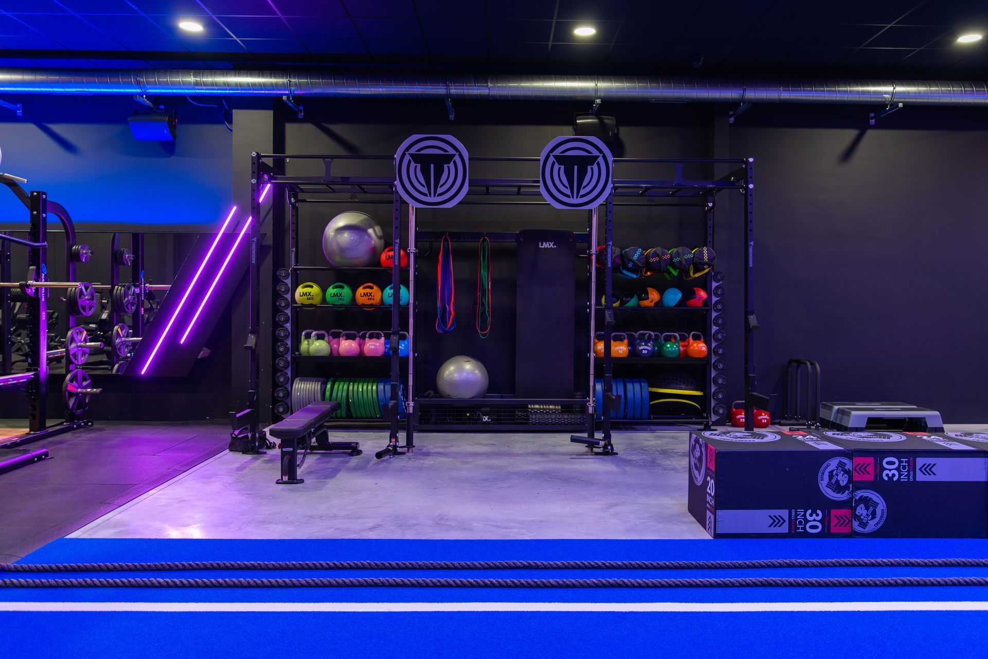Een gymzaal met veel apparatuur en een blauwe vloer.