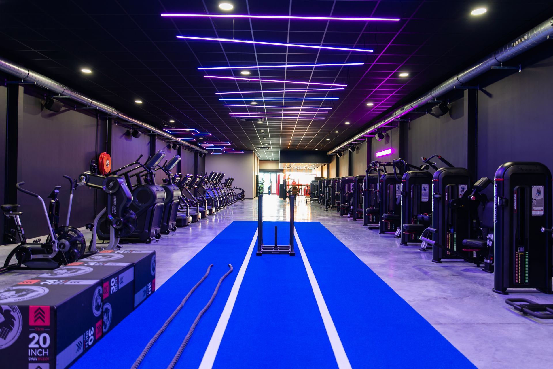 Een sportschool vol met fitnessapparatuur en een blauwe mat.