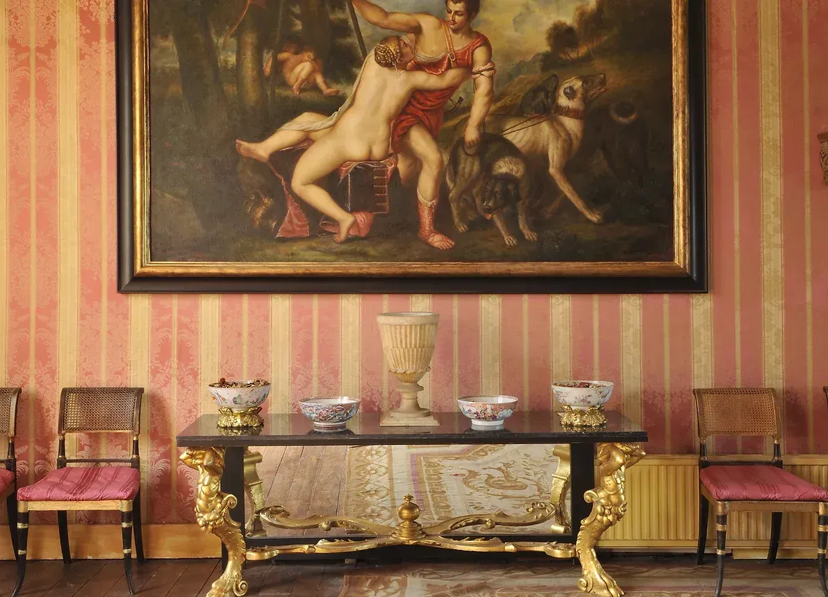A room with a table and chairs and a painting on the wall