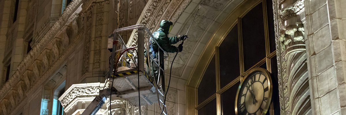 A person on scaffolding beside a clock tower at night.