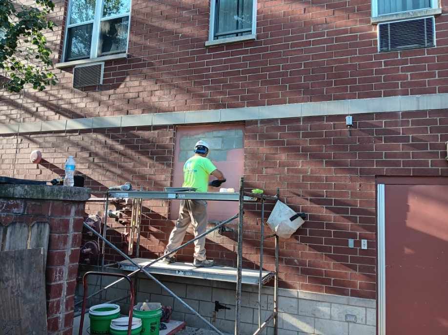 Construction worker on scaffolding, repairing a brick wall.