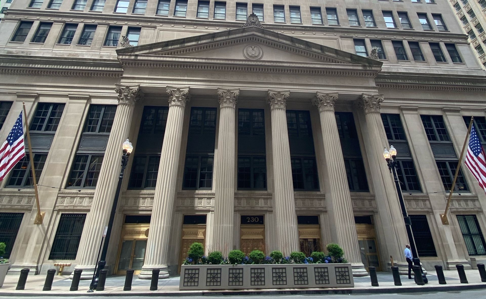 A grand stone building with tall columns and American flags flanking the entrance at 225.