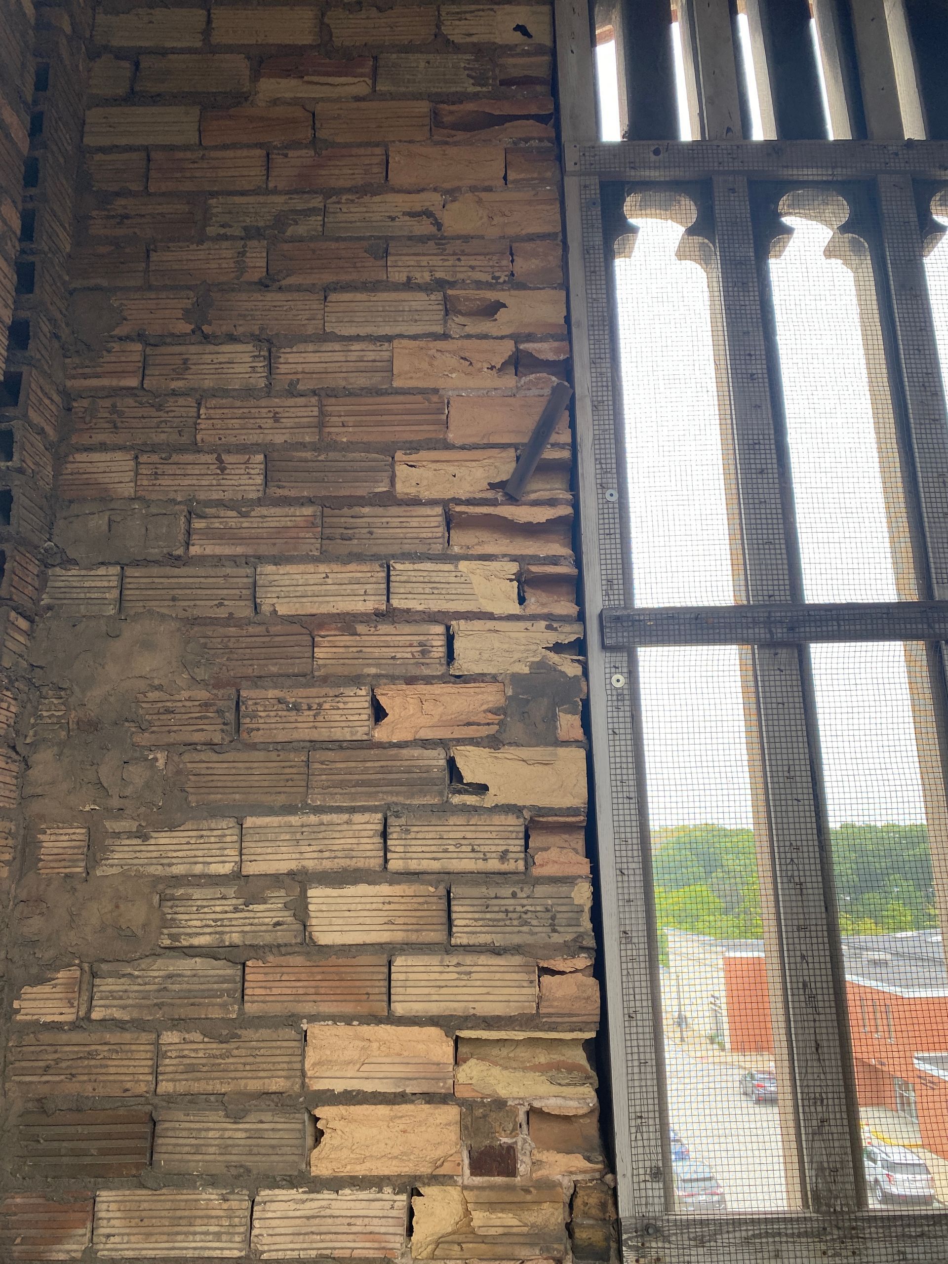 Close-up of weathered brick wall showing freeze-thaw damage, with gaps and uneven surfaces, 
