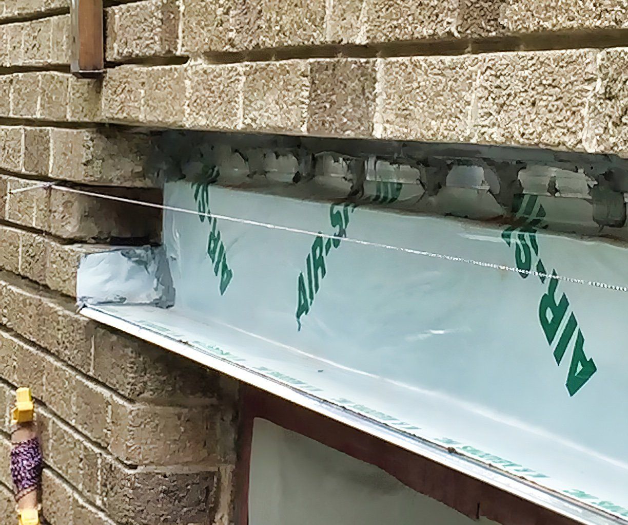 Exterior window construction with a wrapped metal flashing and brickwork.